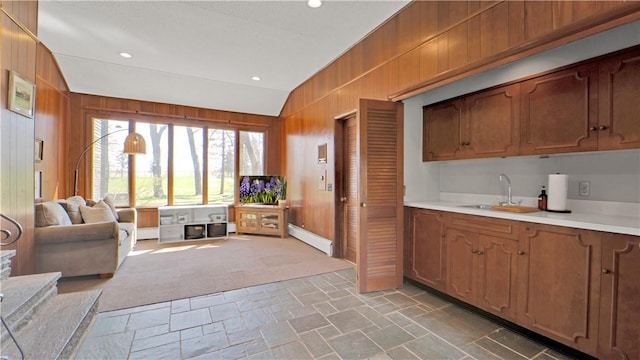 kitchen featuring a sink, stone finish flooring, wooden walls, and light countertops