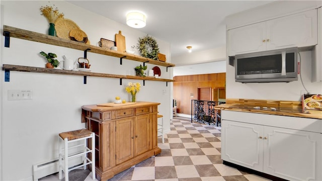 kitchen with open shelves, black electric stovetop, white cabinetry, stainless steel microwave, and light floors
