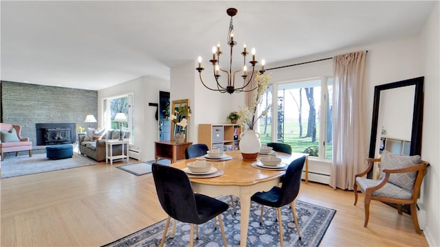 dining area featuring a chandelier, a baseboard heating unit, light wood-style flooring, and a baseboard radiator