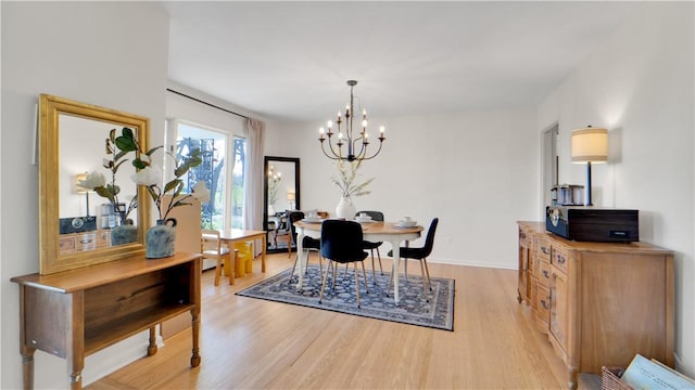 dining space with light wood-type flooring, baseboards, and a chandelier