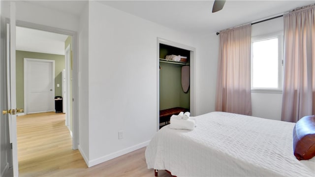 bedroom featuring baseboards, light wood-style flooring, ceiling fan, and a closet