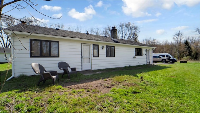 back of house with a yard and a chimney