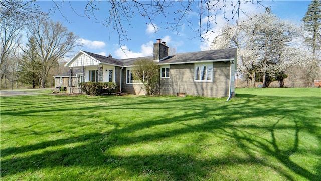 back of house featuring a lawn, brick siding, and a chimney