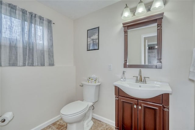 half bath featuring toilet, vanity, and baseboards