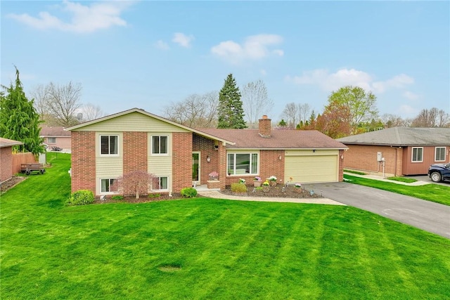 split level home featuring a chimney, brick siding, aphalt driveway, a front lawn, and an attached garage