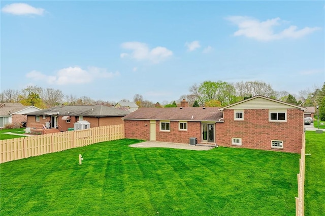 rear view of property with a patio, fence, a yard, and brick siding