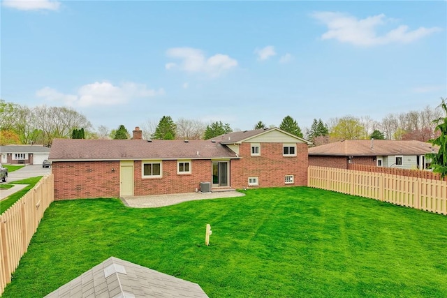 back of property featuring a yard, a patio area, a fenced backyard, and brick siding