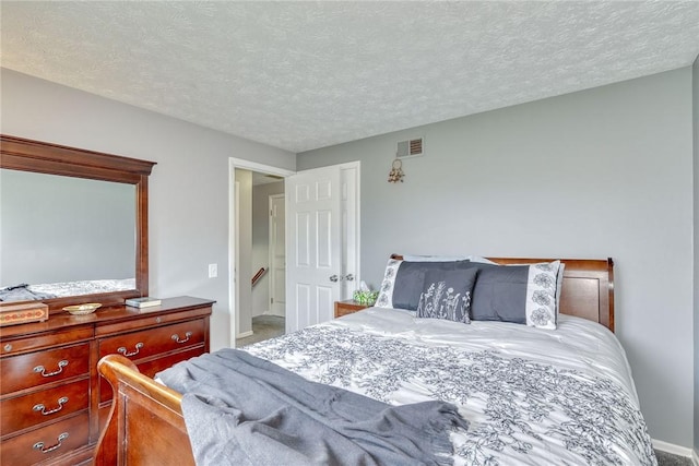 carpeted bedroom with a textured ceiling, visible vents, and baseboards