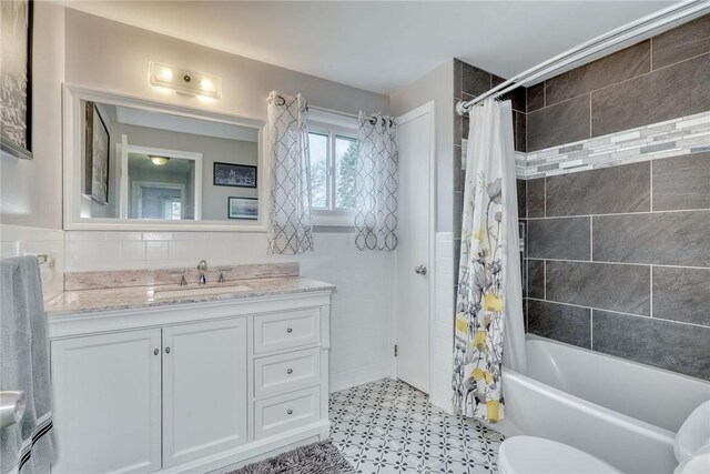 full bath featuring toilet, shower / bath combination with curtain, tile walls, and vanity