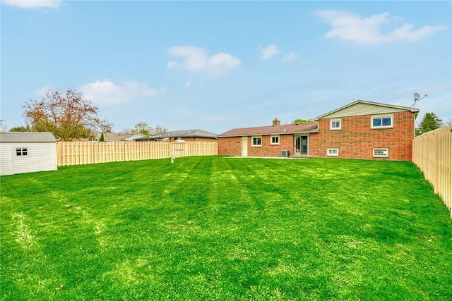 view of yard with a storage unit, an outbuilding, and a fenced backyard