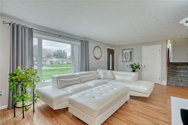 living area with stairs, light wood-style flooring, and baseboards