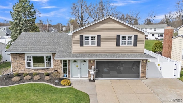 view of front of property with roof with shingles, a front lawn, stone siding, a gate, and driveway