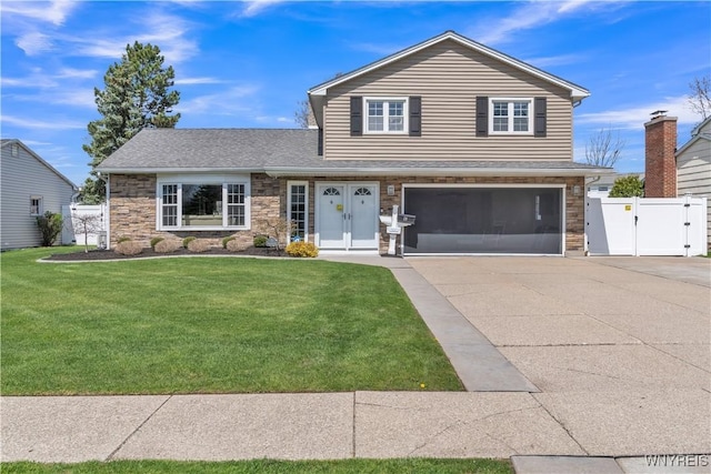 view of front of house featuring fence, stone siding, a front yard, a gate, and concrete driveway