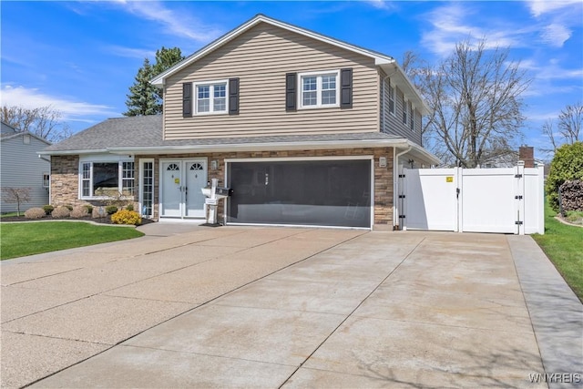 view of front of property featuring driveway, a gate, stone siding, and a garage