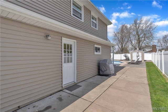 view of patio / terrace with an outdoor structure, a fenced in pool, a fenced backyard, and a storage unit