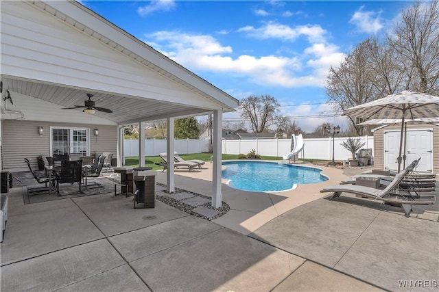 view of pool featuring a fenced backyard, a water slide, ceiling fan, and a patio area