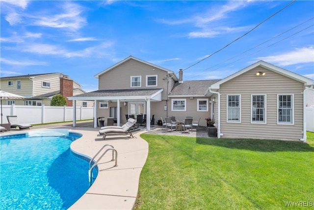 back of property with fence, a patio, a shingled roof, and a lawn