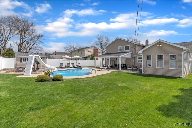 back of property with an outbuilding, a patio area, a fenced in pool, a fenced backyard, and a yard
