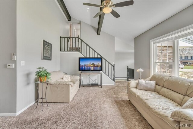 carpeted living room featuring baseboards, lofted ceiling with beams, stairs, and a ceiling fan
