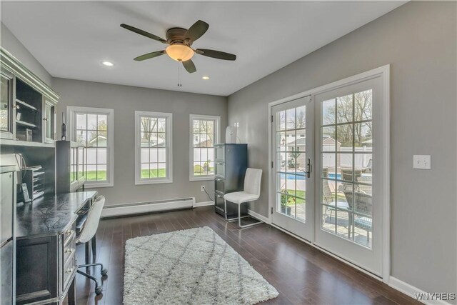 office space featuring ceiling fan, a baseboard heating unit, dark wood-style floors, and baseboards