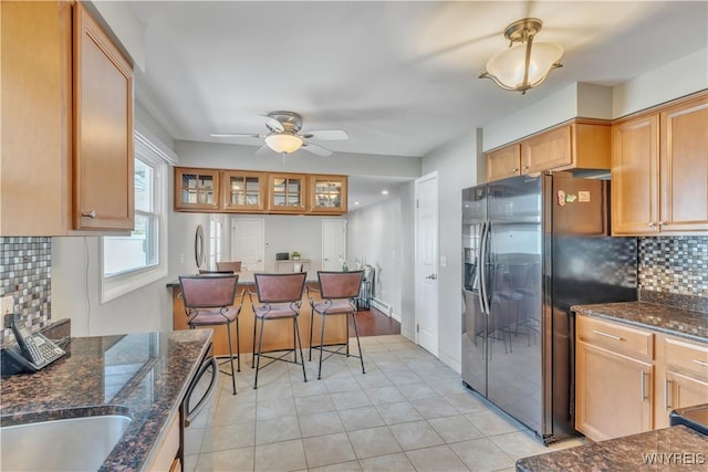 kitchen with dark stone countertops, black dishwasher, a ceiling fan, tasteful backsplash, and stainless steel refrigerator with ice dispenser