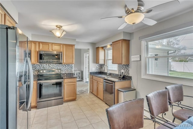 kitchen with a ceiling fan, a sink, appliances with stainless steel finishes, and tasteful backsplash