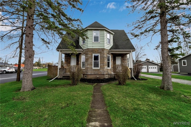 view of front of house with a detached garage, a shingled roof, a front lawn, and stone siding