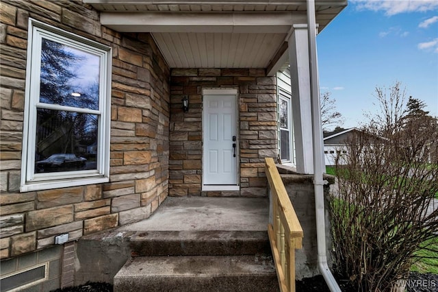 view of exterior entry featuring covered porch and stone siding