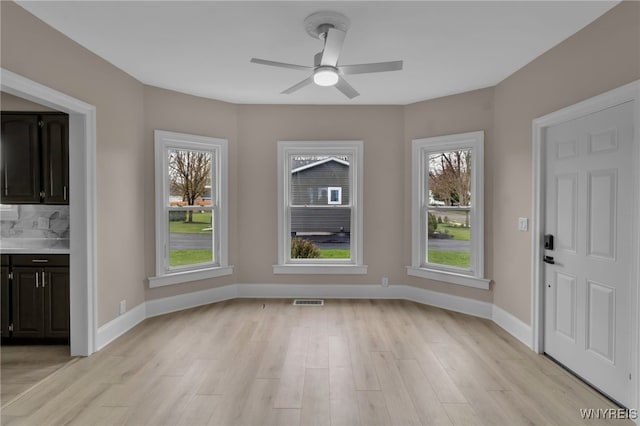 unfurnished dining area with baseboards, visible vents, ceiling fan, and light wood-style flooring