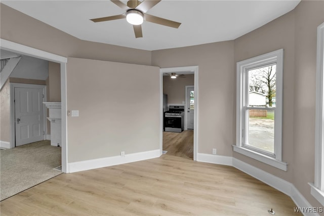 unfurnished room with baseboards, ceiling fan, light wood-style floors, and plenty of natural light