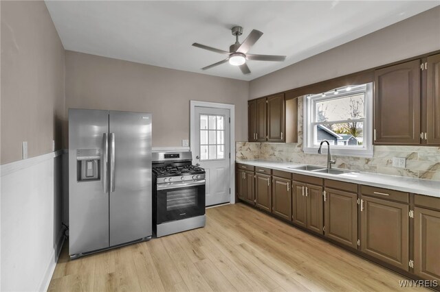 kitchen with light wood finished floors, a sink, stainless steel appliances, a ceiling fan, and light countertops