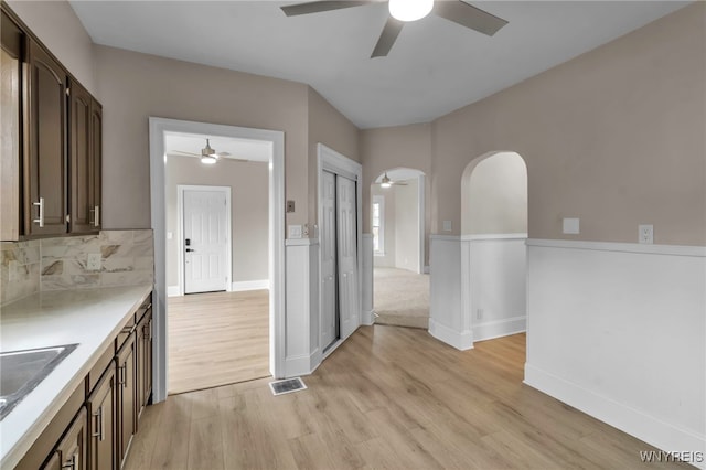 kitchen with light wood finished floors, a ceiling fan, dark brown cabinets, and light countertops