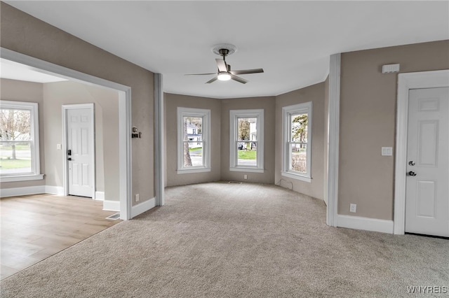 unfurnished living room with baseboards, visible vents, ceiling fan, and carpet flooring