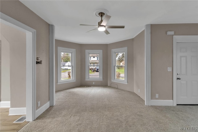 empty room with visible vents, ceiling fan, carpet flooring, and baseboards