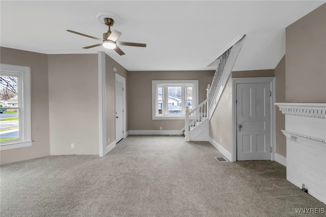 unfurnished living room with carpet flooring, a ceiling fan, visible vents, and stairs