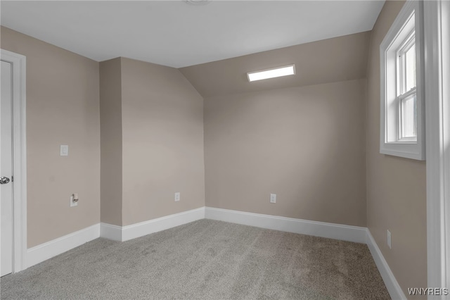 carpeted empty room featuring baseboards and lofted ceiling