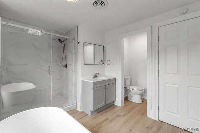 full bath featuring wood finished floors, toilet, vanity, visible vents, and a marble finish shower