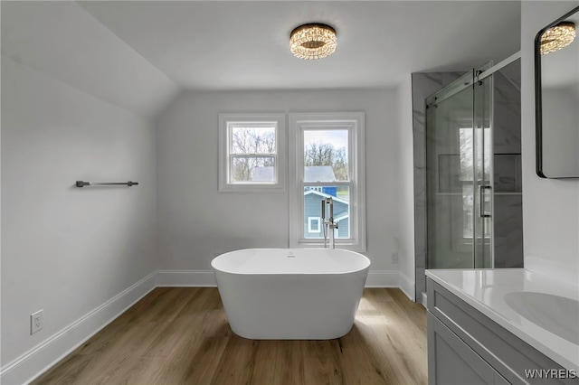full bathroom with a shower stall, a soaking tub, wood finished floors, and baseboards
