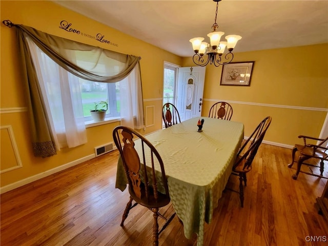 dining area with baseboards, visible vents, wood finished floors, and a chandelier