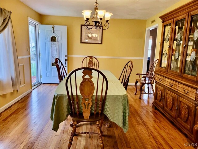 dining area with baseboards, a notable chandelier, and hardwood / wood-style floors