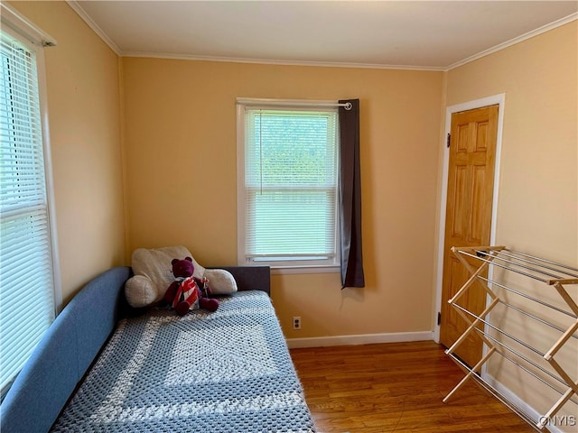 bedroom featuring baseboards, ornamental molding, and wood finished floors