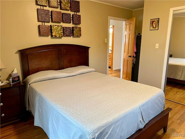 bedroom featuring crown molding, wood finished floors, and a closet