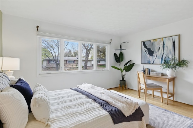 bedroom featuring baseboards, wood finished floors, and multiple windows