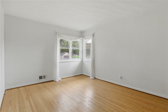 empty room featuring visible vents, baseboards, and wood finished floors