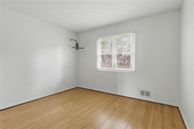 empty room featuring visible vents, baseboards, and wood finished floors