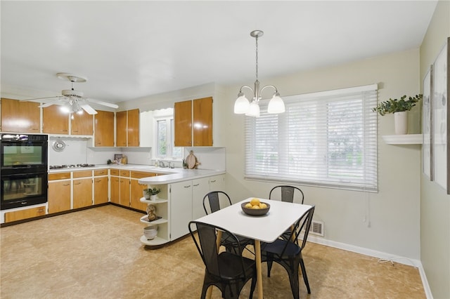kitchen with dobule oven black, open shelves, light countertops, ceiling fan with notable chandelier, and hanging light fixtures