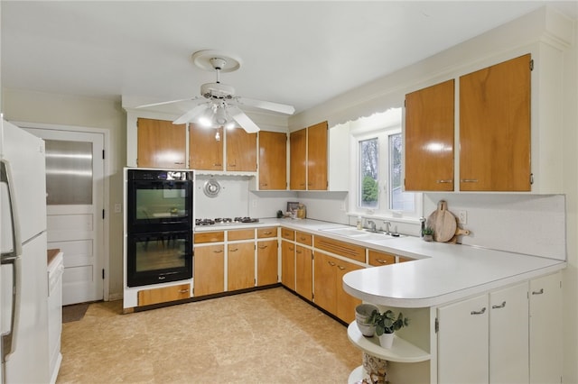 kitchen with dobule oven black, a ceiling fan, light floors, light countertops, and a sink