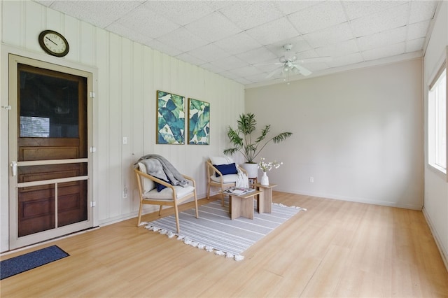 living area with baseboards, ceiling fan, and wood finished floors