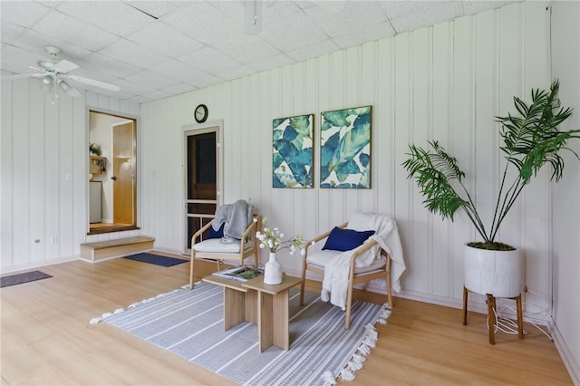 sitting room with ceiling fan, baseboards, and light wood-type flooring