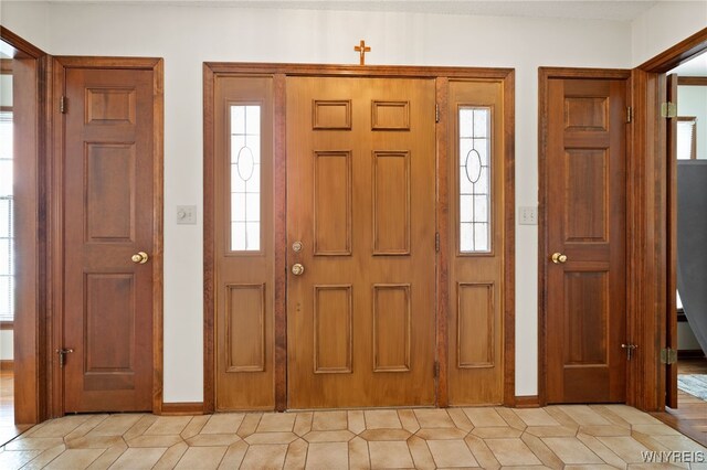 foyer entrance featuring baseboards and light tile patterned flooring